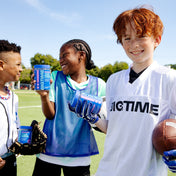 Children on a sports field holding 'Bigtime' products and a football.