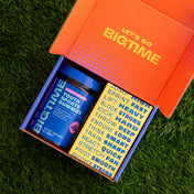 Open box with 'BIGTIME' youth sports gummies on a grass background