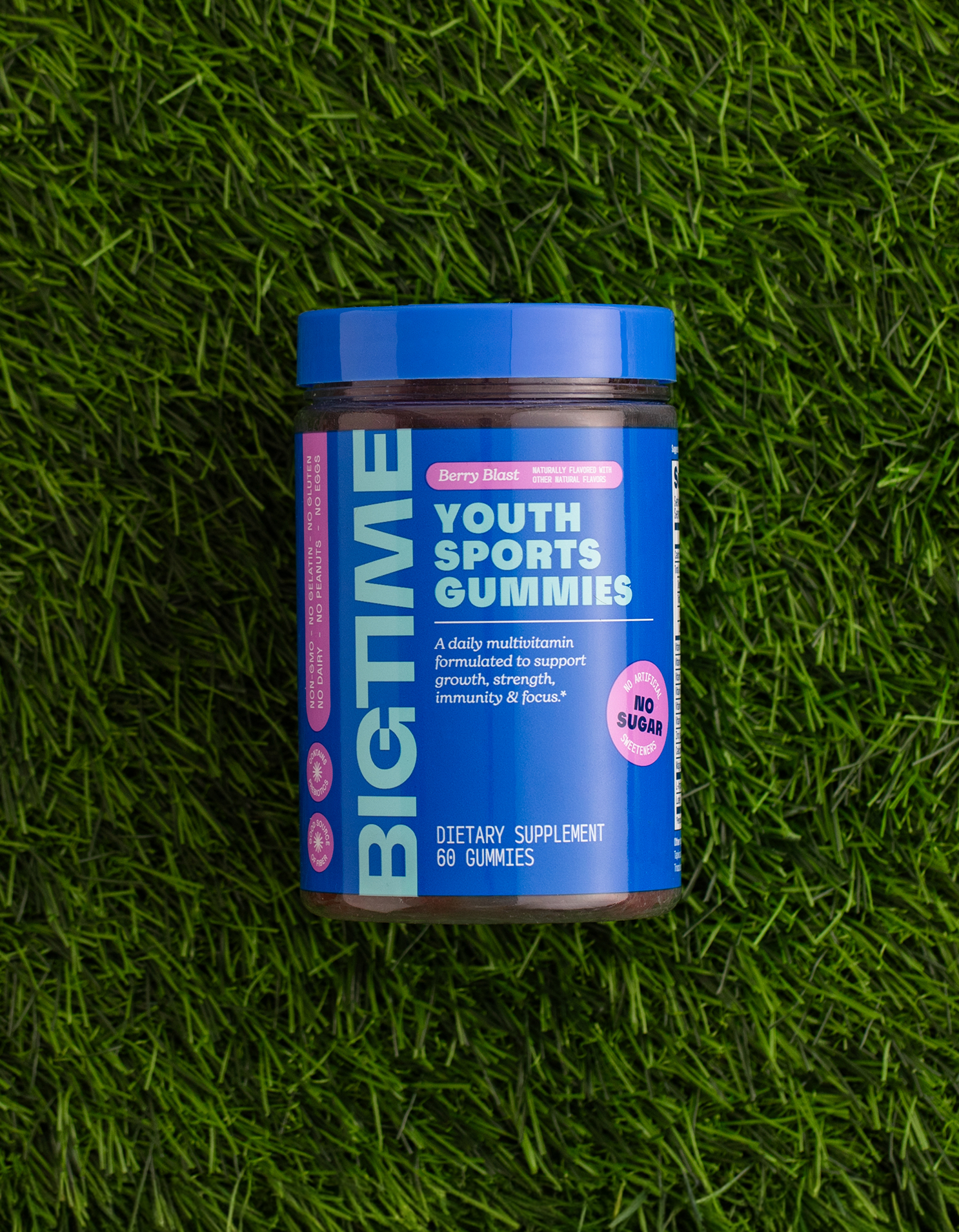 Blue container of 'BIGTIME Youth Sports Gummies' on green grass